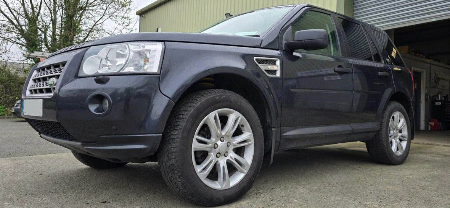 Low angle front view of a dark blue Land Rover Freelander 2 with tinted rear windows outside the Gorey workshop